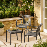 Outdoor patio setting with two chairs and a small table on a stone patio.