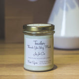 Candle jar with a label on a wooden surface