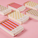Set of small notebooks with colorful designs on a pink background